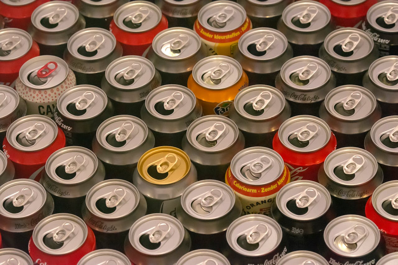 Top view of various aluminum soda cans lined up in colorful rows, highlighting recycle potential.
