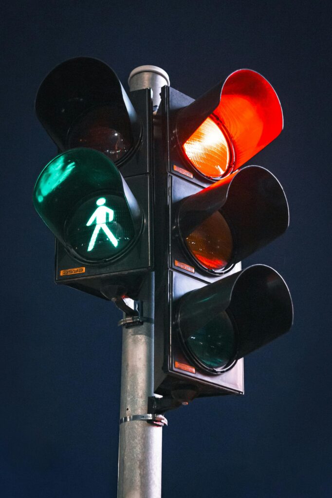 Close-up of a traffic light at night showing green pedestrian signal, with red lights glowing.