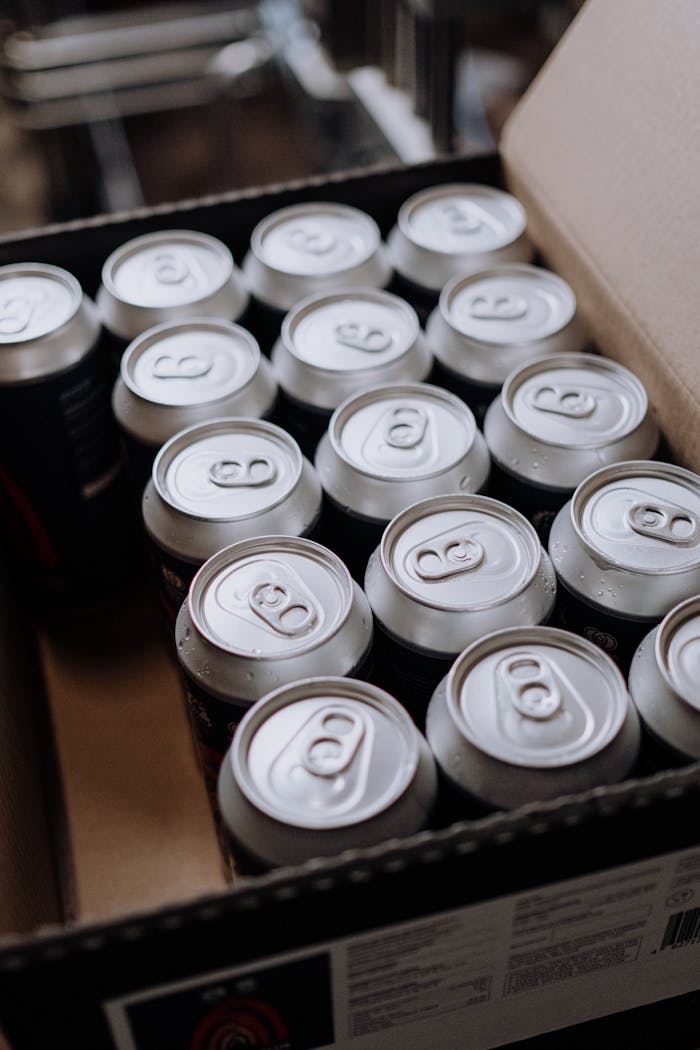 Close-up of aluminum drink cans packed neatly in a cardboard box, displayed from above.